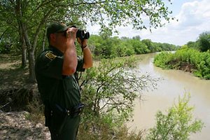 A CBP Border Patrol agent scans the area with binoculars